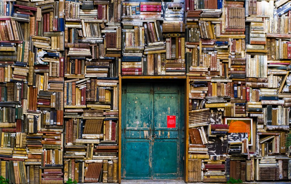 Super-stuffed bookshelves surrounding a blue-green door.